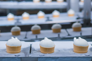 Icecream automatic production line - conveyor belt with ice cream cones at modern food processing factory. Food dairy industry, manufacturing, engineering and automated technology equipment concept