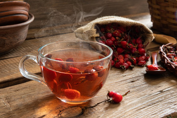 Rosehip tea on wooden background with red fruits