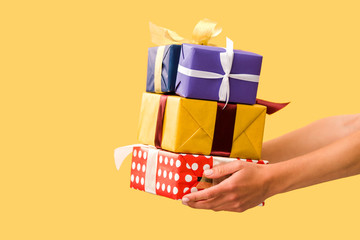 partial view of girl holding gift boxes isolated on yellow