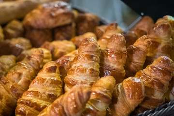 Assortment of freshly baked croissants for sale on counter of shop, market, cafe or bakery. Dessert, pastry, breakfast, sweet food and traditional french cuisine concept