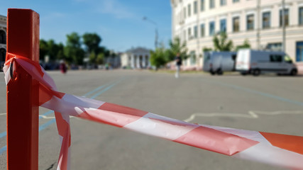 Red white does not cross the tape and the metal pole. Signal red and white tape hanging on a metal fence, danger, warning. Ribbon and metal red post. Forbidden tape encloses an unsafe area.