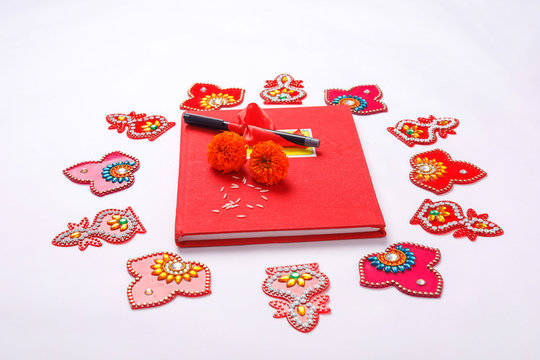  Red accounting note book , diya, and flower rangoli on white background