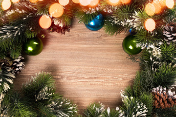 Fototapeta na wymiar Christmas tree branch wreath with blue and green baubles and yellow lights bokeh and wooden background