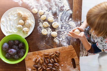 Little girl preparing plum dumplings at home