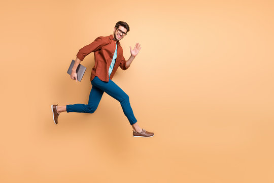 Full Length Body Size View Of His He Nice Attractive Cheerful Cheery Glad Content Guy Jumping In Air Carrying Laptop Running Fast Late Hurry-up Meeting Isolated Over Beige Color Pastel Background