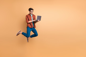 Fototapeta na wymiar Full length body size view of his he nice attractive cheerful cheery successful brunet guy jumping in air using laptop home-based job isolated over beige color pastel background