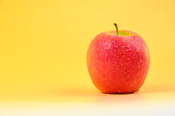 Wet red apple isolated on orange to white gradient background