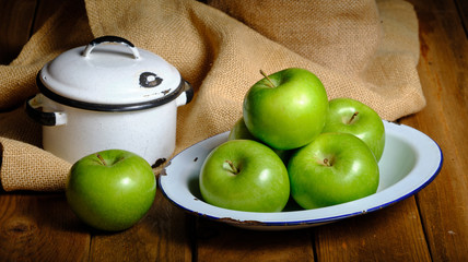 Still life of green apple fruit on old wooden background and decoration of pots, porcelain trays and burlap