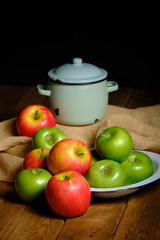 Still life of green and red apple fruit on old wooden background and decoration of pots, porcelain trays and burlap