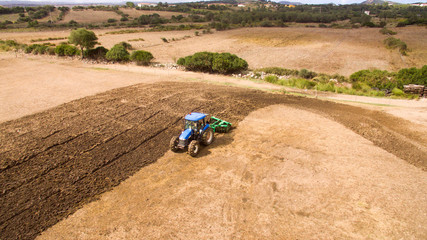 aerial view drone of blue tractor with plow in operation in the field