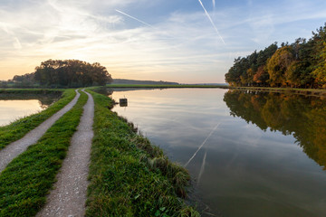 Abendstimmung mit Weihern, Feldweg, Spiegelungen und Gegenlicht