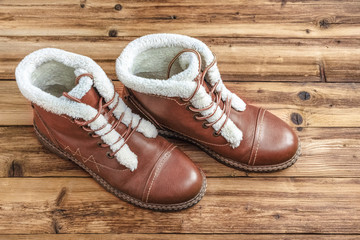 A pair of winter brown boots on a wooden background.