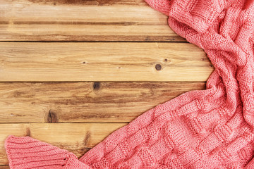 Knitted pink warm blanket on wooden background with space for text. Top view.