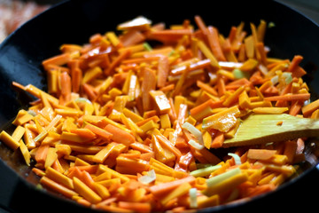 Cooking carrot, pumpkin, zucchini nad leek in wok. Selective focus, close-up.