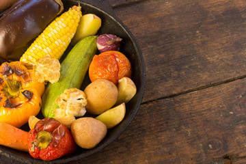 Baked vegetables potato carrot pepper onion corn on the cob eggplant cauliflower squash on wooden table