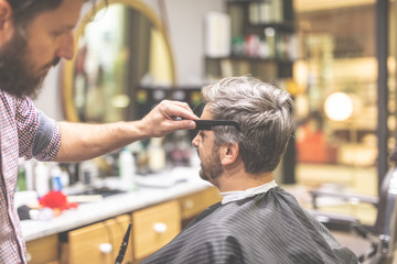 Man in barber chair, hairdresser styling his hair.