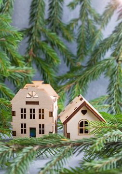 Christmas tree branches with mini houses on gray background.