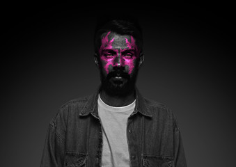 Discover what's inside you. Close up portrait of young man isolated on black studio background. Bright neon light on the face. Halloween, scary look theme, october holidays, horror concept.