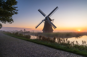 Fototapeta na wymiar Windmill during a foggy, autumn sunrise in the Dutch countryside. Krimstermolen, Zuidwolde.
