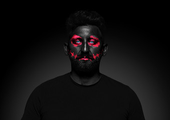 Discover what's inside you. Close up portrait of young man isolated on black studio background. Bright neon light on the face. Halloween, scary look theme, october holidays, horror concept.
