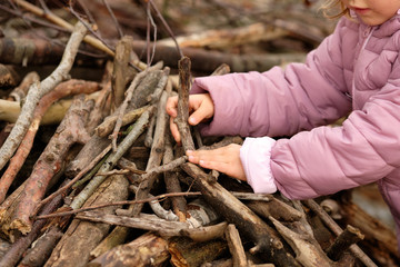 Mid section of a 4 year old child girl in purple warm clothing building something with wooden...