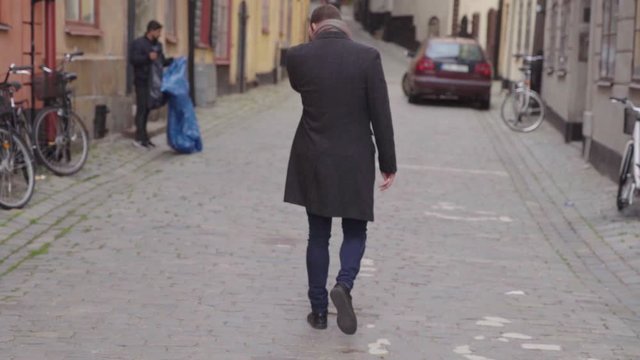 Young man in overcoat turning an walking away