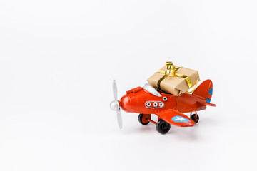 Miniature toy red retro airplane with little gift on white background. Metal model.