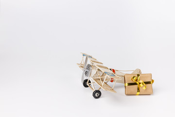 Miniature toy retro airplane with little gift on white background. Metal model.