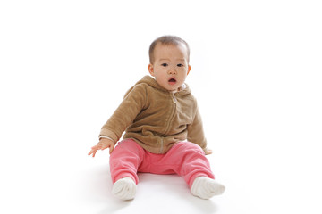 Baby sitting on the ground playing in the white background