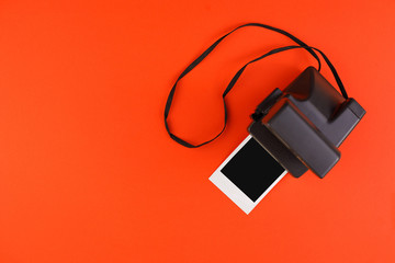 Instant photo frame and camera on a red background. Concept of preservation of memories. Flat lay.