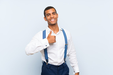 Young handsome brunette man with suspenders over isolated background giving a thumbs up gesture