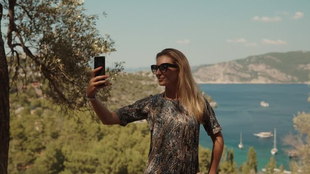 Girl Taking Selfie On Smartphone On Seashore.Girl Takes Pictures On Smartphone On Seashore.Woman Taking Selfie When Stay On Cliff.Woman Taking Self Photo And Answer To Video Call On Sea Cliff.