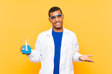 Scientific man holding a laboratory flask over isolated background with shocked facial expression