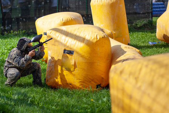 Paintball game. Warriors in protective suits. Training ground. Masks on the faces. Marker shooting.