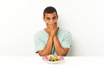 Young handsome man with salad in a table with surprise facial expression