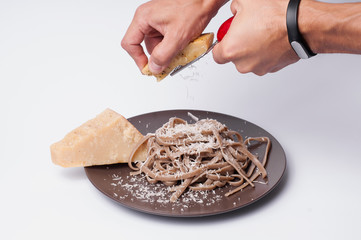 Man rubs parmesan cheese on spaghetti.Studio shooting