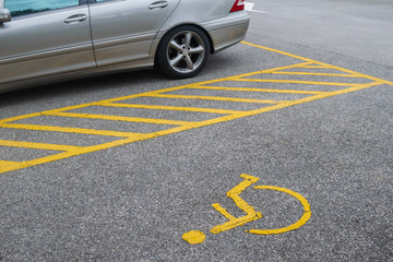 Silver car parking near handicapped parking sign area at asphalt parking lot
