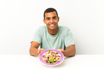 Young handsome man with salad in a table