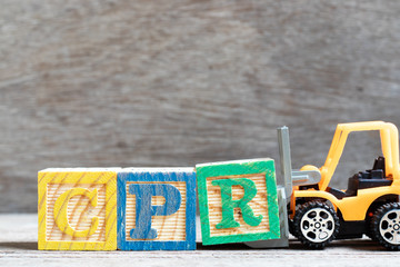 Toy forklift hold letter block r to complete word CPR (abbreviation of Cardiopulmonary resuscitation) on wood background