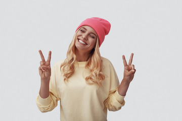 Attractive young woman gesturing and smiling while standing against grey background