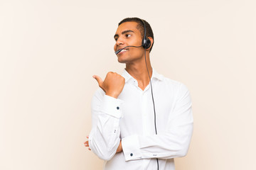 Young brunette man working with a headset pointing to the side to present a product