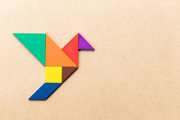 Color tangram puzzle in flying bird shape on wood background