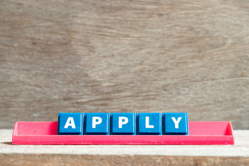 Tile letter on red rack in word apply on wood background