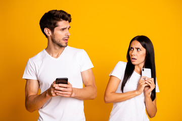 Photo of two people with telephones not trust each other private information wear casual clothes isolated yellow color background