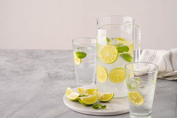 Fresh lemonade with lime and ice cubes in a glass jar.
