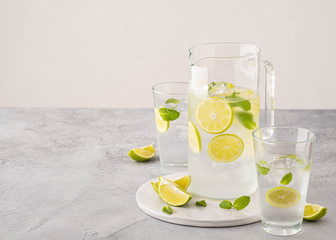 Fresh lemonade with lime and ice cubes in a glass jar.