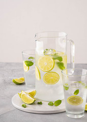 Fresh lemonade with lime and ice cubes in a glass jar.