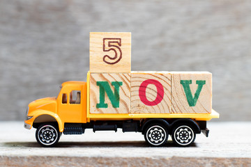 Truck hold letter block in word 5nov on wood background (Concept for date 5 month November)