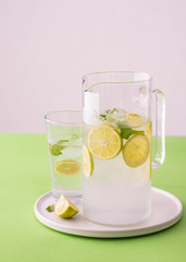 Fresh lemonade with lime and ice cubes in a glass jar.