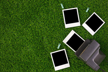 Instant photo frames and a camera on a background of lawn grass. Concept of preservation of memories. Flat lay.